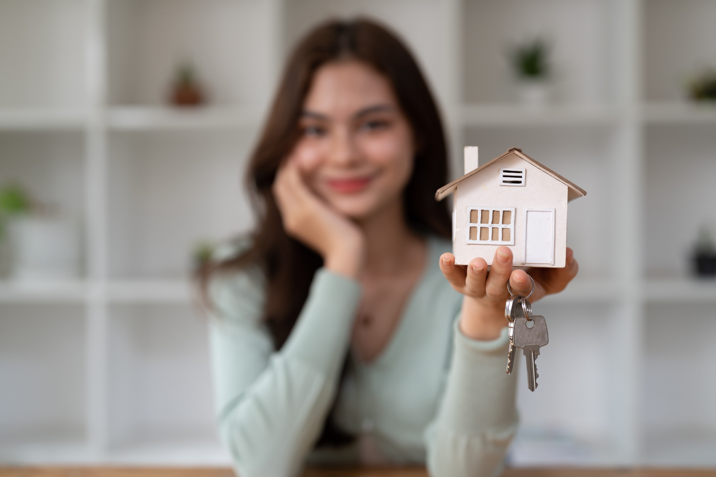 mujer sujeta una casa en miniatura y unas llaves
